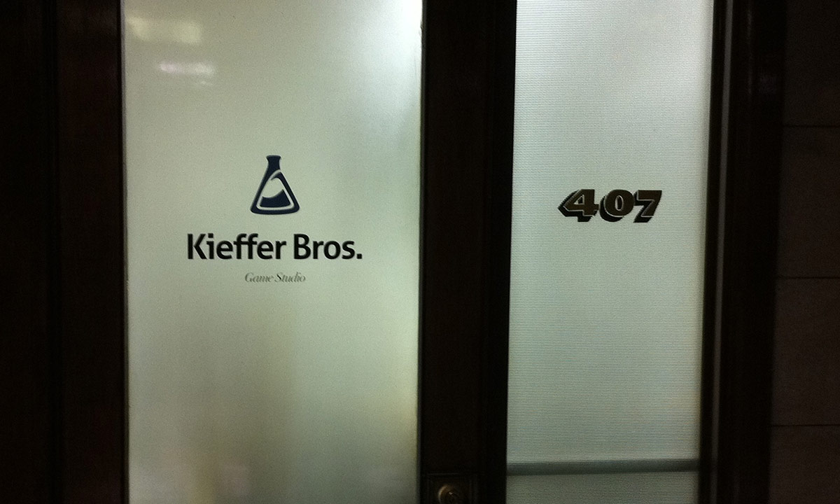 a photo of a frosted glass office door. On the door a sign reads, "Kieffer Bros. Game Studio"
